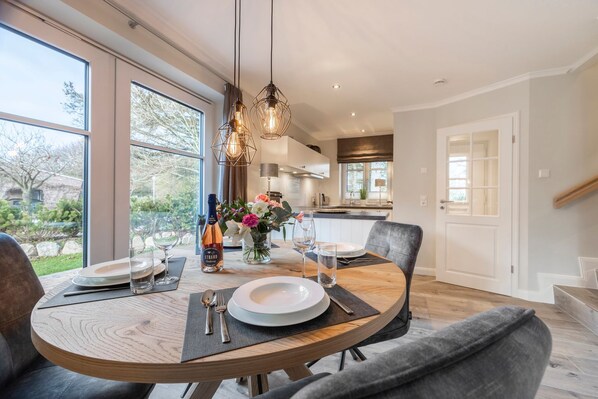 A dining area with a round table, chairs, and a bottle of wine.