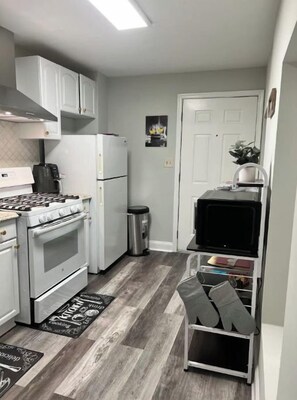 A compact kitchen with white cabinets, a stove, oven, and a microwave.