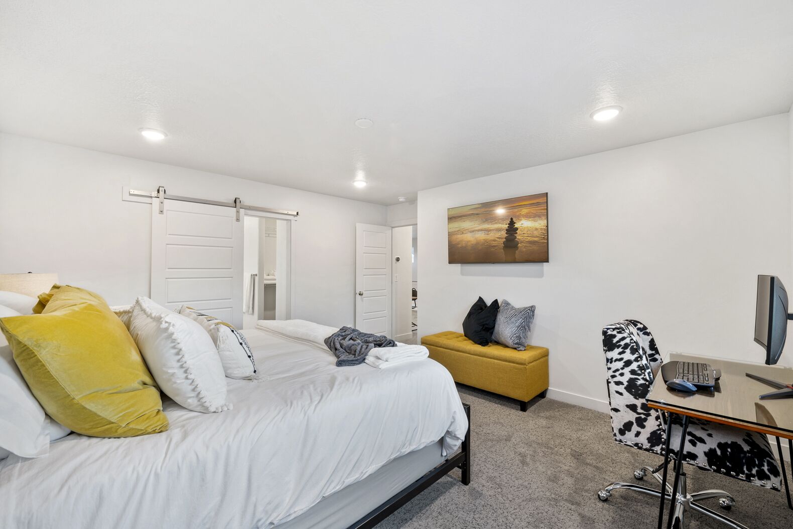 A modern bedroom with a bed, a desk with a computer, and a sofa.
