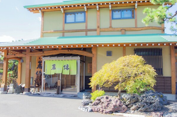 A traditional Japanese building with a green roof, wooden beams, and a sign with Japanese characters.