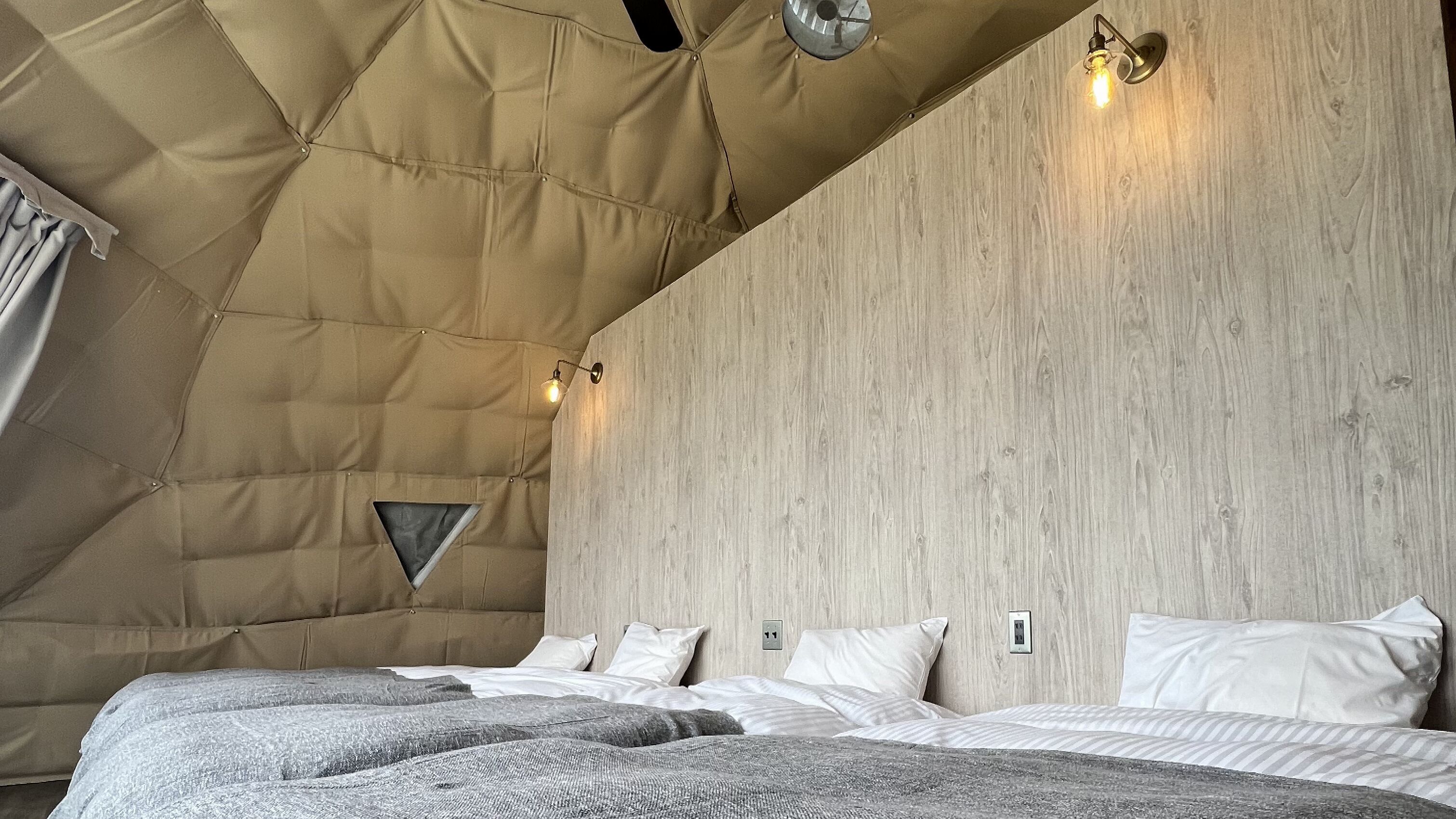 Un dormitorio con un techo alto y acolchado, una pared de madera y una cama con muchas almohadas.