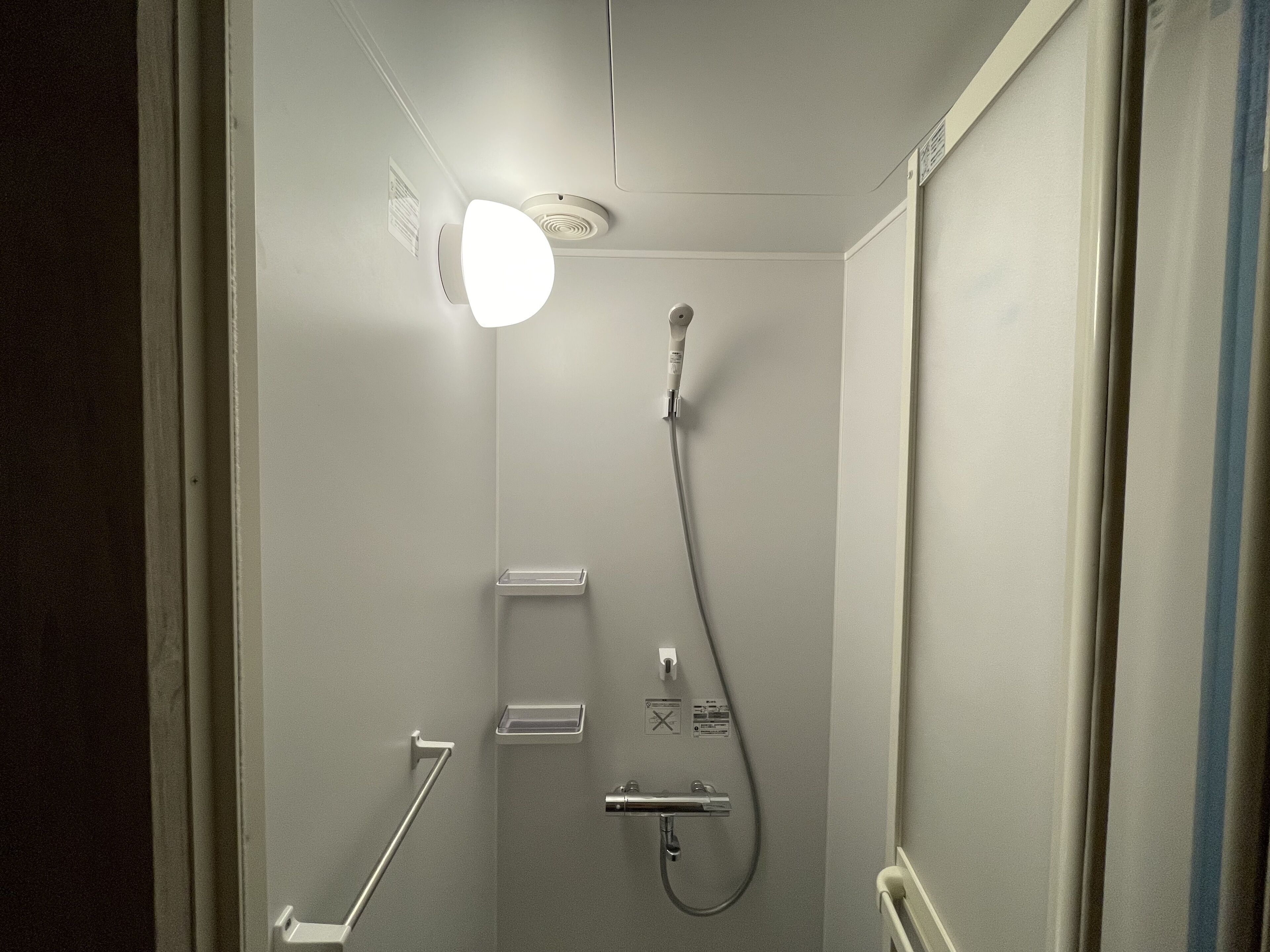 A modern shower with a handheld showerhead and a wall-mounted faucet.