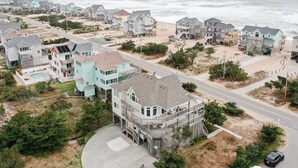 Eine Wohngegend an der Küste mit Häusern nahe am Strand, darunter ein Haus mit großzügigem Balkon und Schwimmbad.