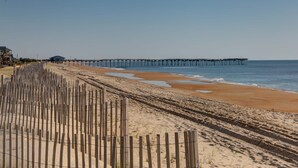 Ein Strand mit einer Holzbrücke und einem Steg, der ins Wasser hineinreicht.