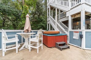 A patio area with white chairs, a small table, a hot tub, and a wooden deck. - 7725- Sun Kissed - Avon Retreat | Pool, Hot Tub & Theater Room (Avon)