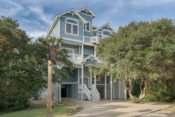 A two-story house with a front porch, a staircase leading to the second floor, and a basketball hoop in the front yard. - 7725- Sun Kissed - Avon Retreat | Pool, Hot Tub & Theater Room (Avon)