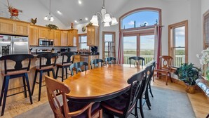A spacious kitchen with wooden cabinets, a large island, and a dining area with a wooden table and chairs. - 7725- Sun Kissed - Avon Retreat | Pool, Hot Tub & Theater Room (Avon)