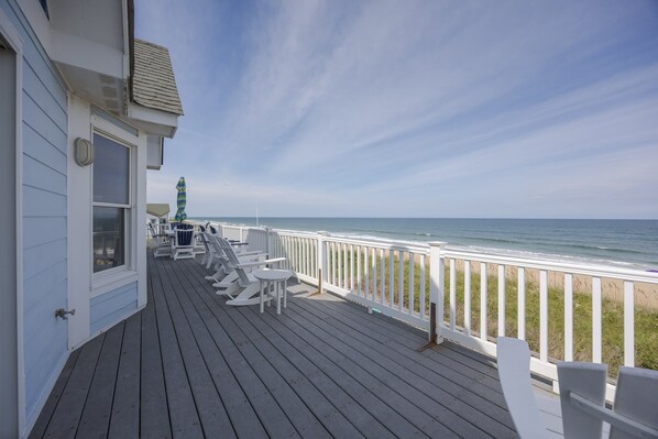 A wooden deck with white railings overlooking a beach.