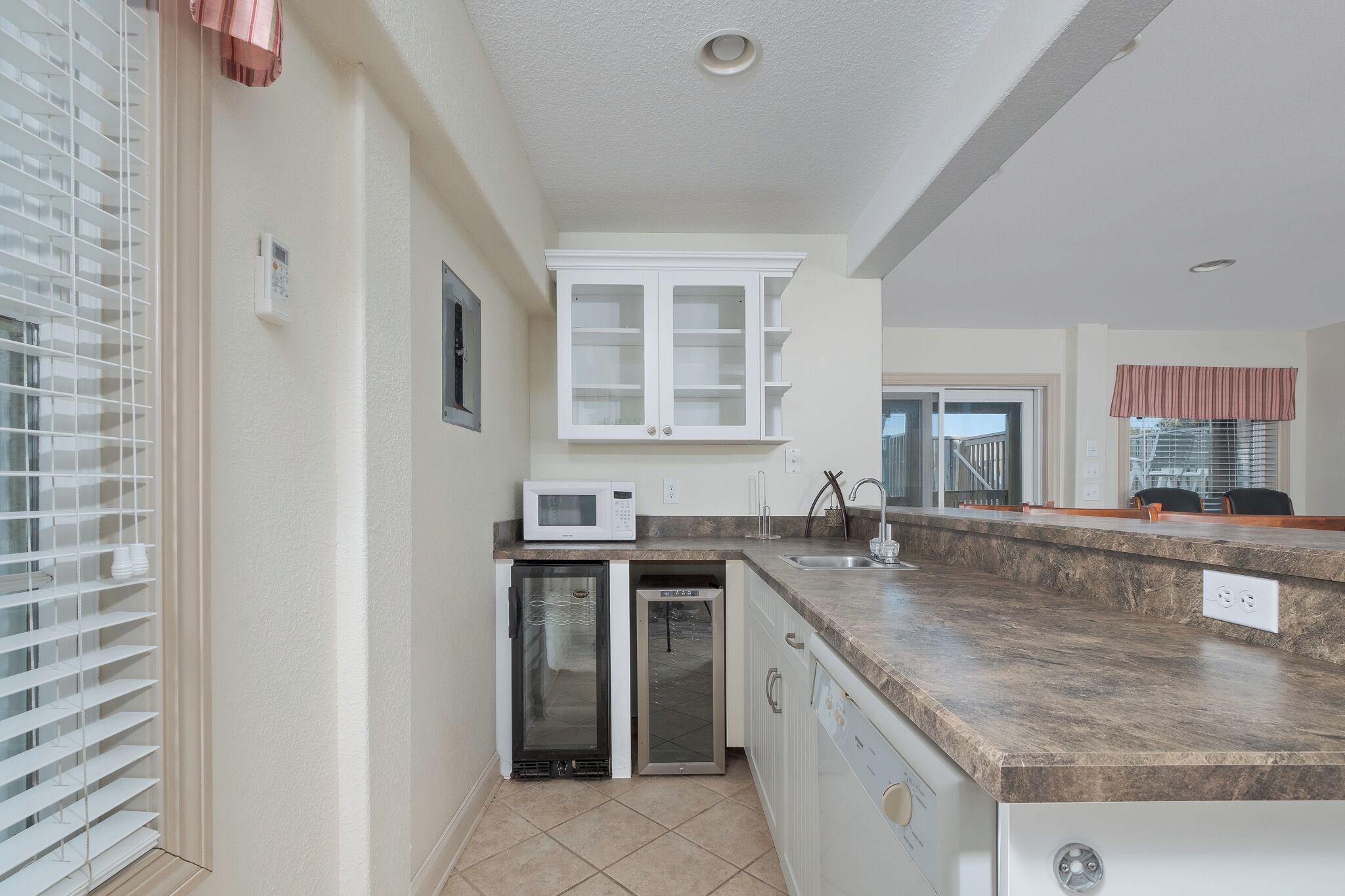 A compact kitchen with white cabinets, a microwave, a mini-fridge, and a dishwasher.
