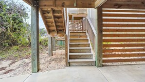 A wooden staircase leading to a covered area with a wooden fence. - 5176- Sandy Bottoms - Coastal Escape | Dog Friendly + Hot Tub (Kill Devil Hills)