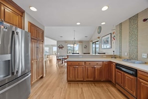 A modern kitchen with wooden cabinets, stainless steel appliances, and a large island.