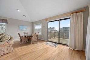 A spacious room with a dining area, a sofa, and a view of a deck.