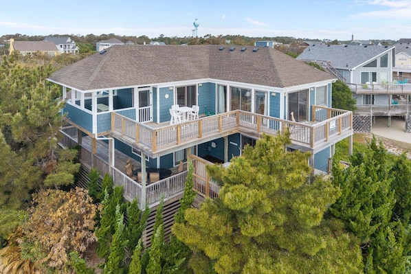 A multi-level waterfront property with balconies, outdoor seating, and a view of the surrounding area.