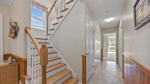 Una escalera con peldaños de madera y barandillas blancas, que lleva a una puerta.