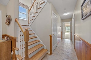 Un escalier avec des marches en bois et une rampe blanche, menant à une porte.