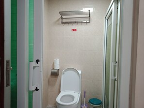 A bathroom with a toilet, a paper towel dispenser, a hand dryer, and a trash bin. - RUJIA CONDOTEL CORP. (Lapu-Lapu)