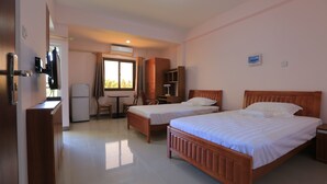 A hotel room with two wooden beds, a small table, a chair, a desk, and a wardrobe. - RUJIA CONDOTEL CORP. (Lapu-Lapu)