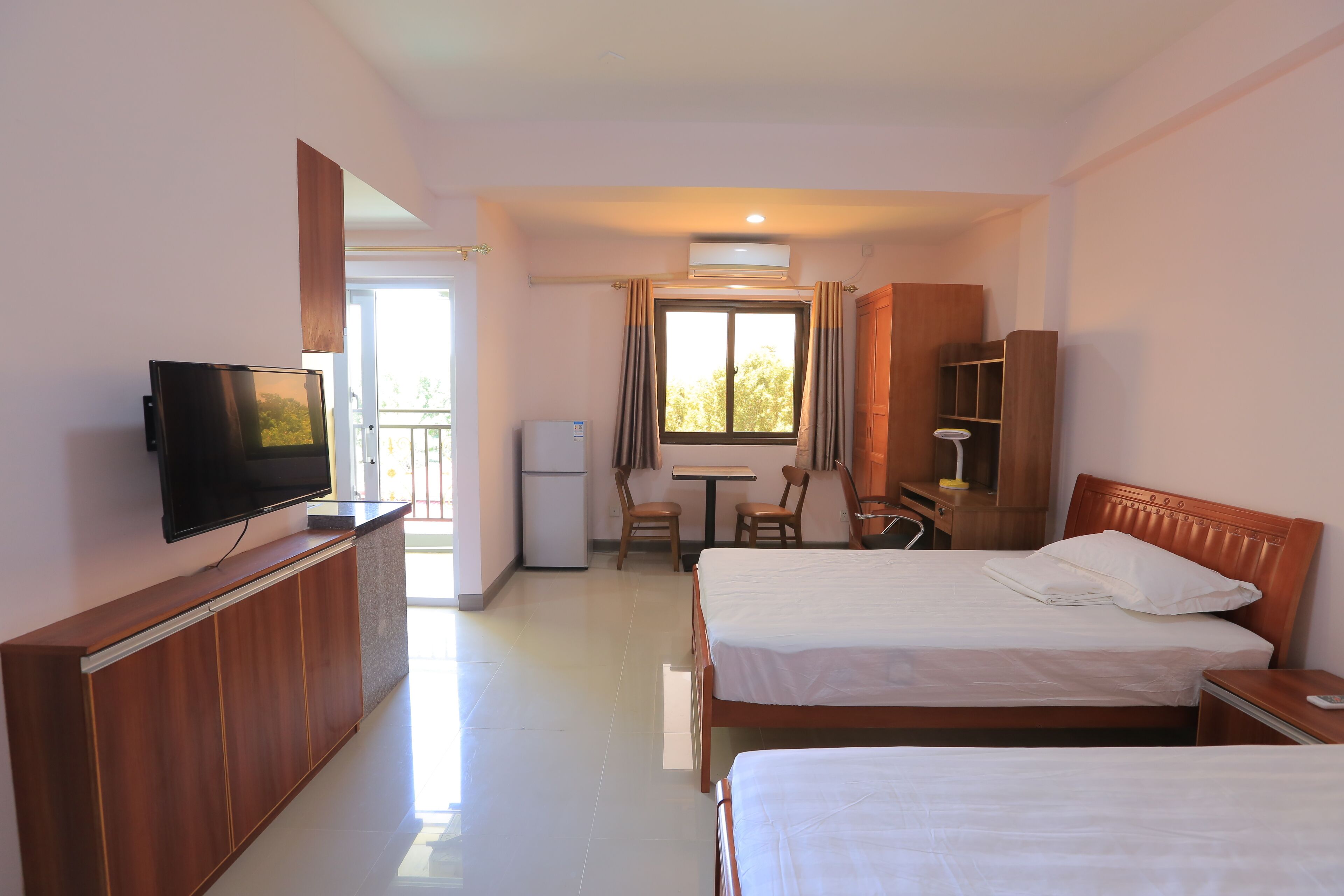 Une chambre d’hôtel avec deux lits, une télévision, un bureau avec une chaise, une armoire et une fenêtre avec des rideaux.