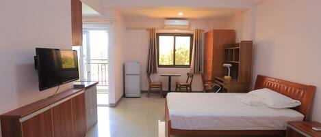 A hotel room with two beds, a television, a desk with a chair, a wardrobe, and a window with curtains.