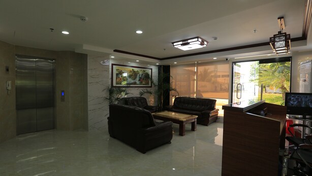 A modern lobby with a reception desk, seating area, and an elevator. - RUJIA CONDOTEL CORP. (Lapu-Lapu)