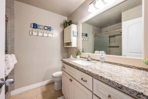 Ein Badezimmer mit Waschbecken, Spiegel, Handtuchhalter und Toilette.