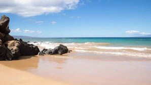 A beach with clear skies, waves, and large rocks. - Ground floor, oceanview, updated coastal style 1 bedroom gem, AC, walk to beach (Kihei)