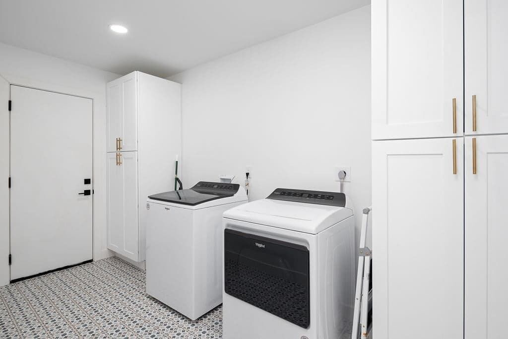 A laundry room with a washing machine, dryer, and cabinets.