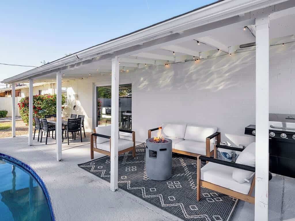 Une terrasse extérieure avec une piscine, un foyer et un espace salon abrité.