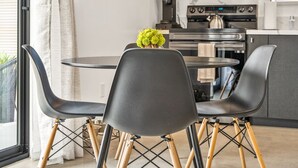A modern kitchen with dark cabinets, a microwave, and a stove. There is a dining table with four chairs and a vase of green flowers. - NEW! HotTub, Hammock, FirePit, BBQ & Paved Driveway (Joshua Tree)