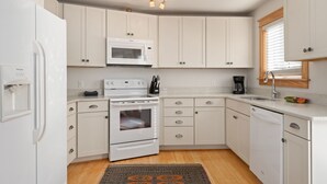 Une cuisine moderne avec des meubles blancs, un four encastré, un four à micro-ondes et un lave-vaisselle.