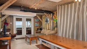 Une pièce chaleureuse avec un plafond en bois, une grande fenêtre et un rideau à rayures.