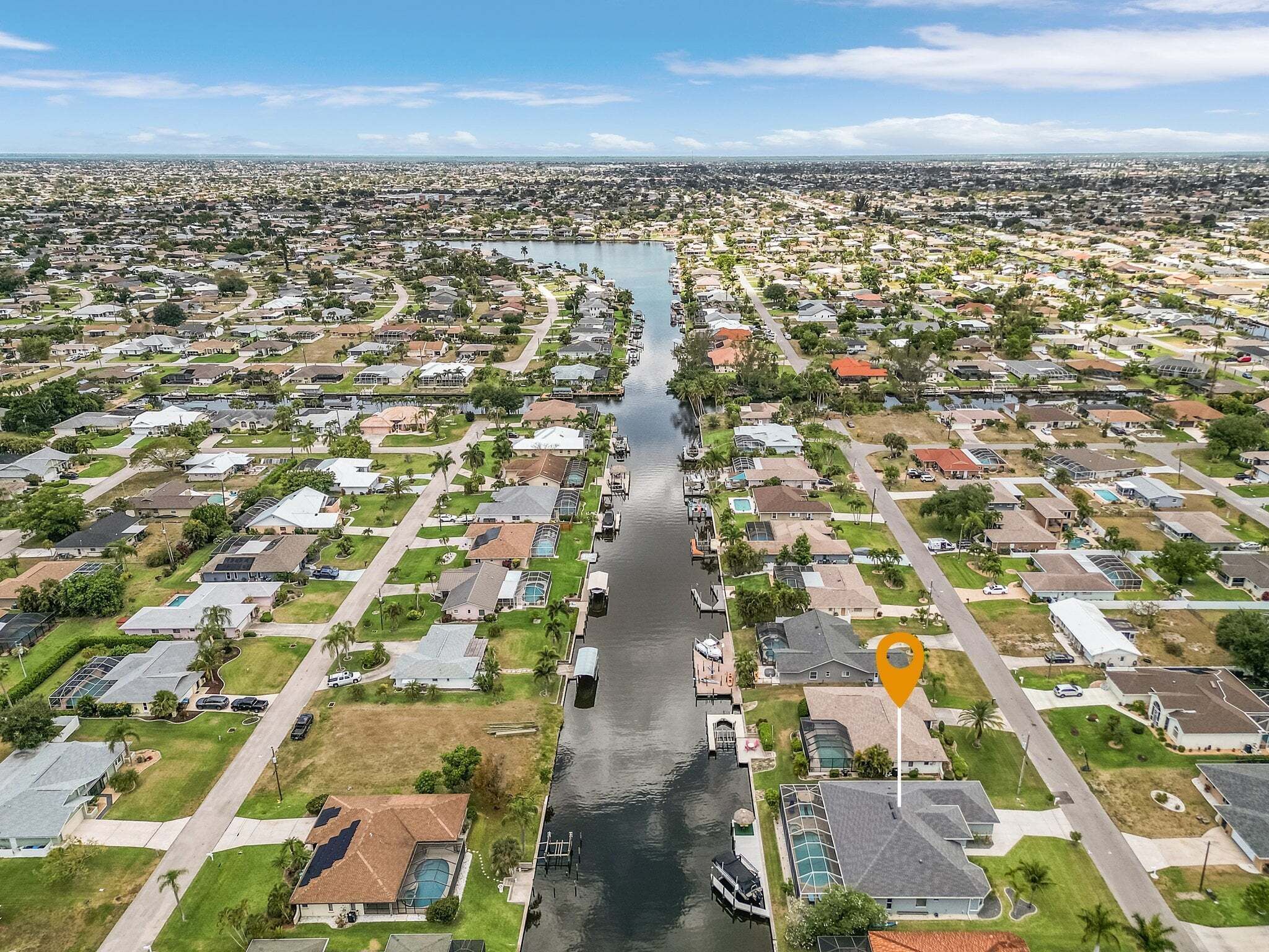 An aerial view of a residential area with houses, a waterway, and a boat dock.