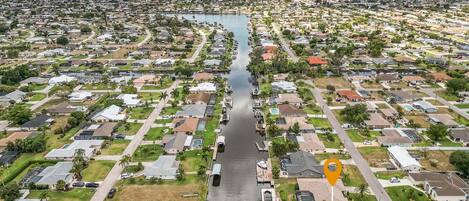 An aerial view of a residential area with houses, a waterway, and a boat dock.