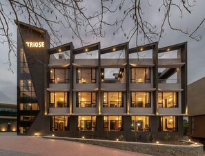 A modern multi-story hotel with a prominent 'TRIOSE' sign, featuring multiple balconies and large windows. - Triose Boutique Hotel (Mawal)