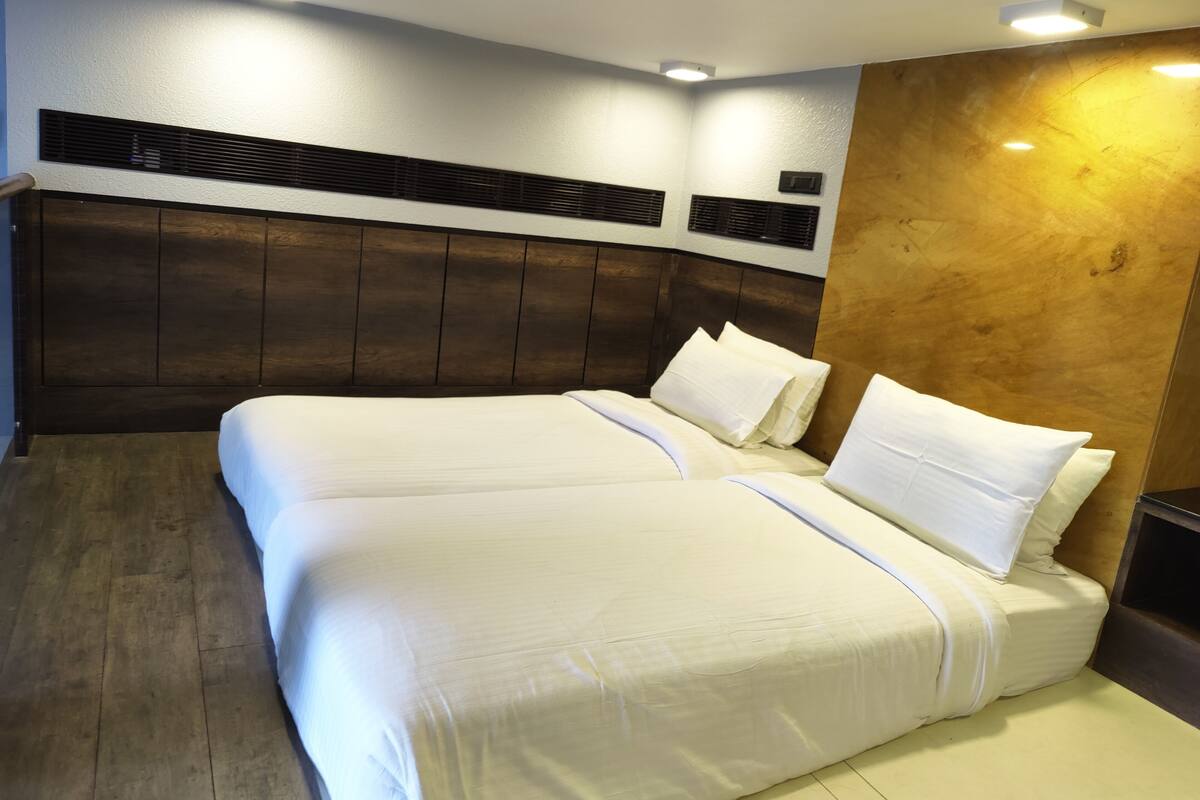 A double bed with white linens in a hotel room.