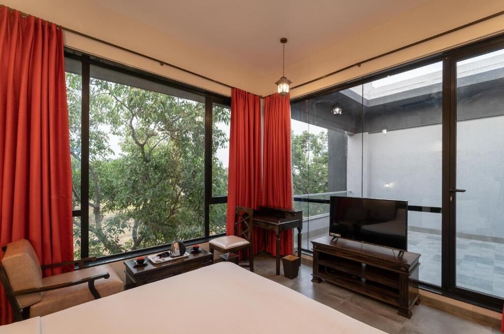 A hotel room with a large bed, a TV, a piano, and a balcony with a glass door.