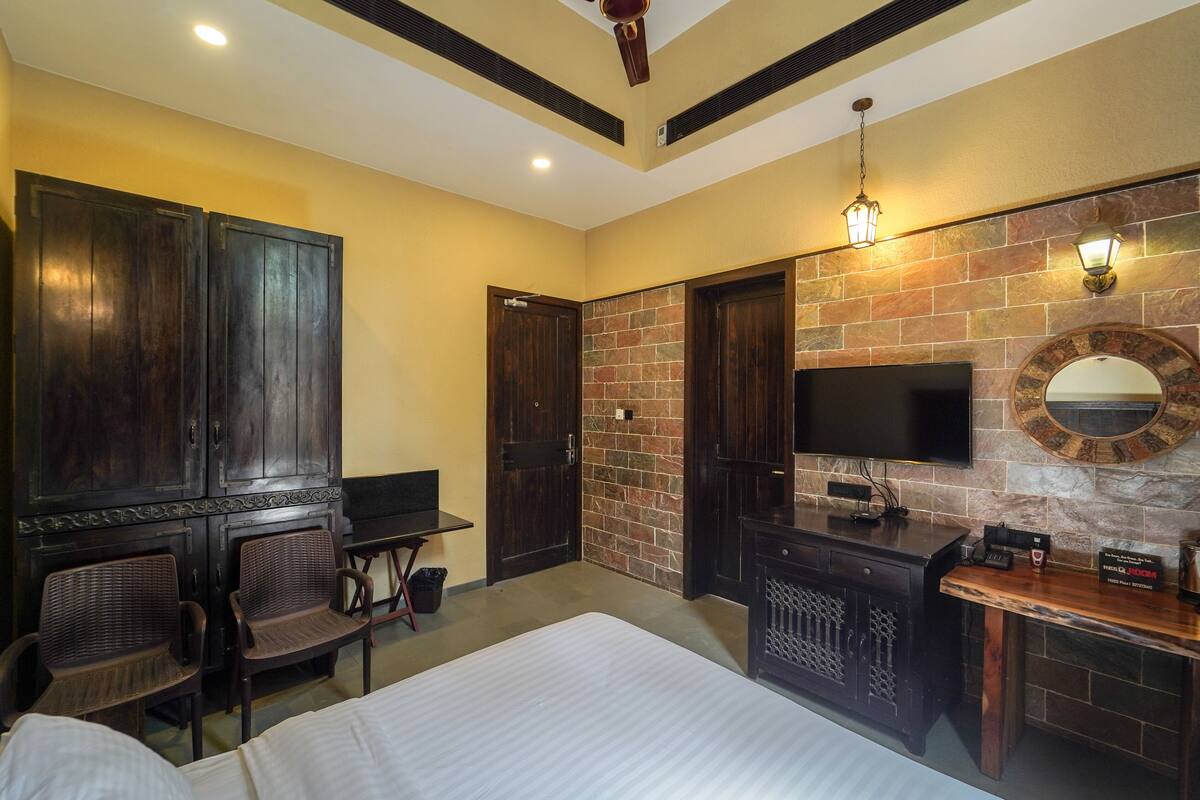 A hotel room with a bed, a desk, a TV, and a brick wall.