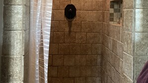 Eine Dusche mit Steinwänden und Duschkopf.
