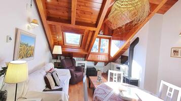 Un acogedor loft con vigas de madera, un sofá, una silla y una mesa de comedor.