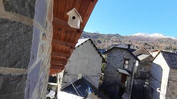 Un edificio de piedra tradicional con techo de madera y un comedero para pájaros.