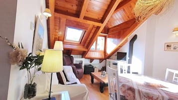 Una habitación acogedora con vigas de madera, un sofá, una mesa y una lámpara.