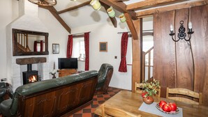 Un salon chaleureux avec une cheminée, des meubles en bois et une table à manger ornée de pommes et d’un vase.
