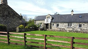 Une maison en pierre avec un mur en pierre et une clôture en bois à l’avant.