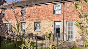 A brick building with a stone facade, a gated entrance, and a small garden area. - The Old Smokehouse (St Austell)