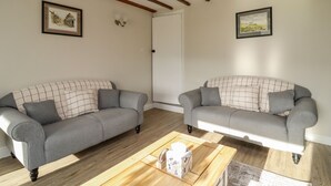 A living room with two grey sofas, a wooden coffee table, and exposed wooden beams on the ceiling. - Sarah's Cottage (Keighley)