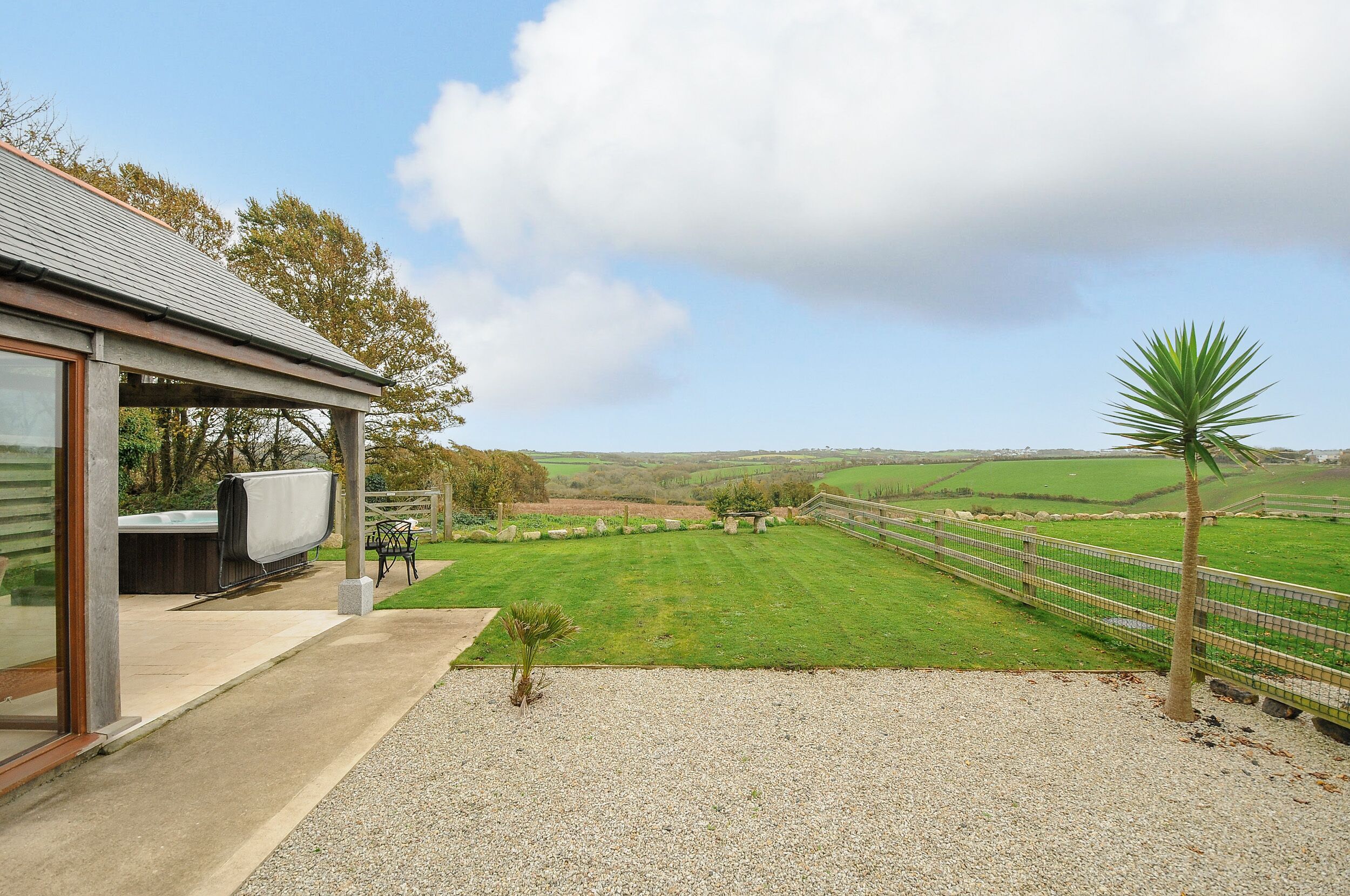 A modern house with a covered patio, a small lawn, and a view of the countryside.