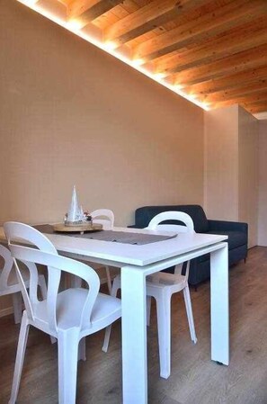 A dining area with a white table and chairs, a small fountain, and a dark-colored sofa.