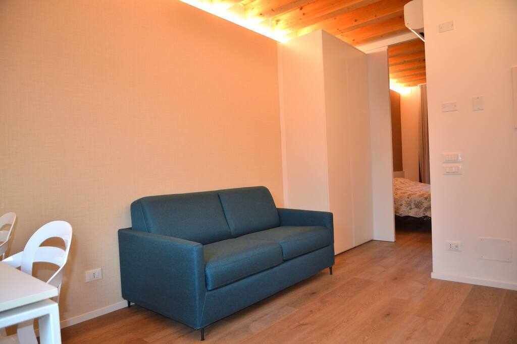Une petite pièce agréable, avec un canapé bleu, une chaise blanche et un plancher en bois.
