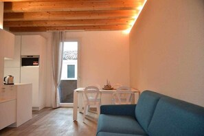 A compact living space with a kitchenette, a dining area with a table and chairs, and a blue sofa.