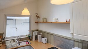 Et moderne køkken med ovenlys, træhylder og basale hårde hvidevarer.